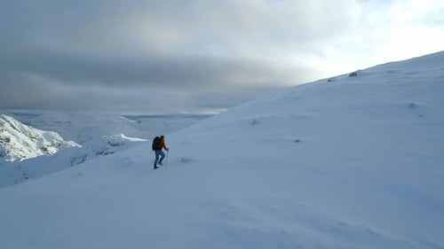 Mountain Climber Walking Towards the Summit of a Mountain