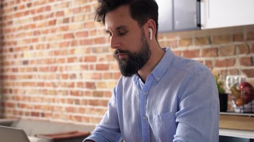 Man Working on Laptop in Home Kitchen