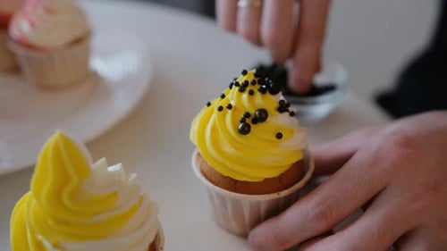 Decorating a Delicious Cupcake With Black Sprinkles
