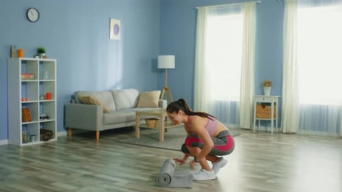 Young Woman Unrolls Yoga Mat and Stretches at Home