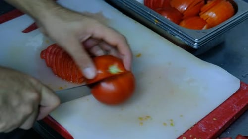 Close-up of Tomatoes Being Sliced on Cutting Board