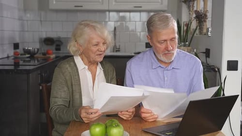 Senior Couple Reviews Documents in Bright Home Kitchen