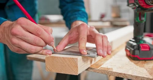 Woodworker Measures and Drills Holes into Wood