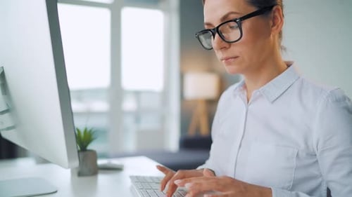 Woman Typing on Keyboard in Bright Office