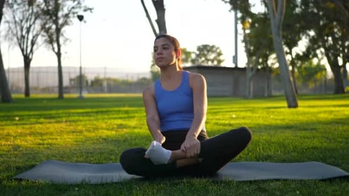 Woman Meditating Outdoors in Park at Sunset