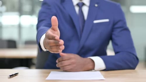 Professional Handshake Offered at Desk in Office