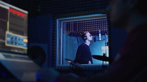 Male Rap Singer with Headphones and Sound Engineer Are Recording a New Song