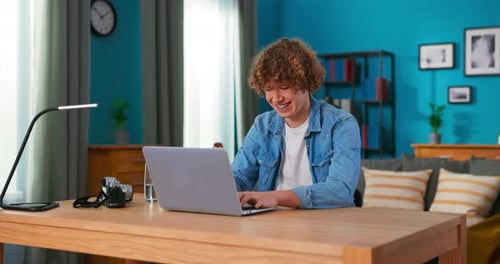 Smiling Teen Typing on Laptop at Desk