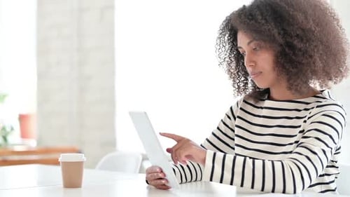 Woman Works on Tablet at Table Indoors