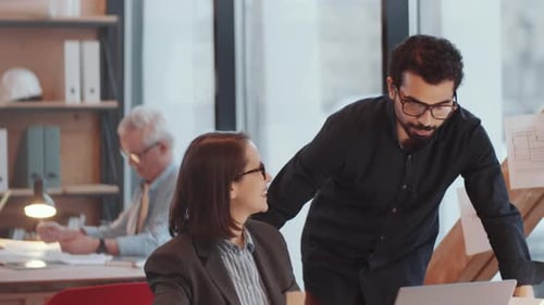 Male and Female Architects Discussing Project on Laptop in Office