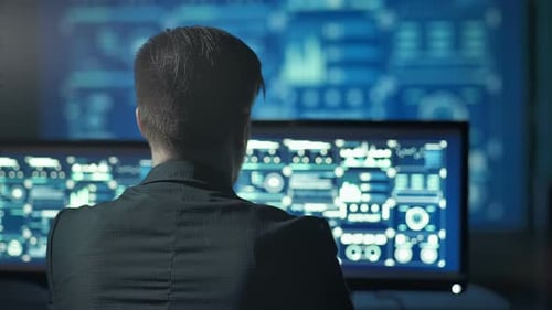 Back View of Programmer Working on Computer in Dark Digital Office