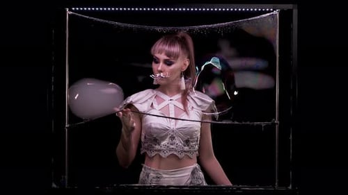 Woman Creating Huge Soap Bubbles in Dark Studio