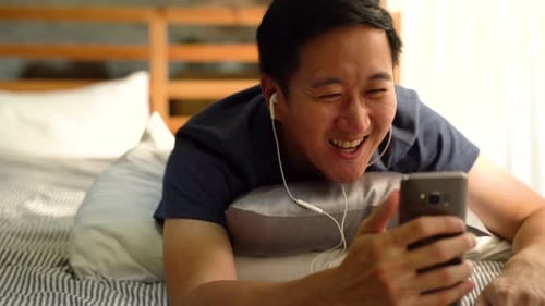 Man Video Calling on Smartphone Lying on Bed