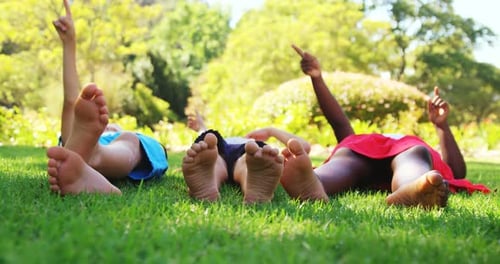 Children Lying on Grass Pointing Upwards on Sunny Day