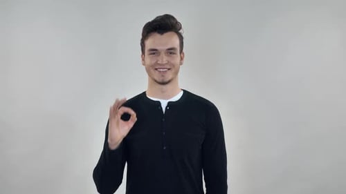 Young Adult Makes Ok Hand Gesture and Smiles