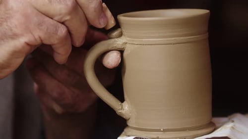 Potter utilise un pinceau lors du traitement de la céramique dans un atelier en gros plan
