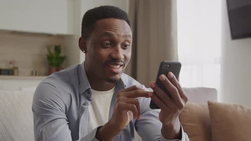 Man Smiling at Smartphone in Bright Indoor Setting