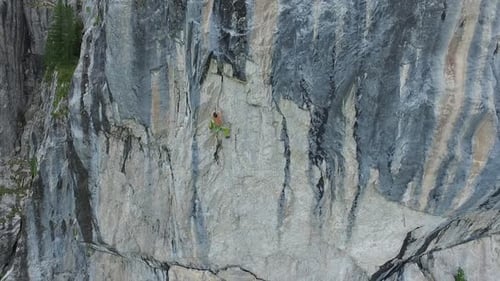 Aerial drone view of a man rock climbing up a mountain.
