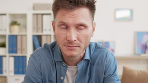 Man Crying and Rubbing Face Indoors