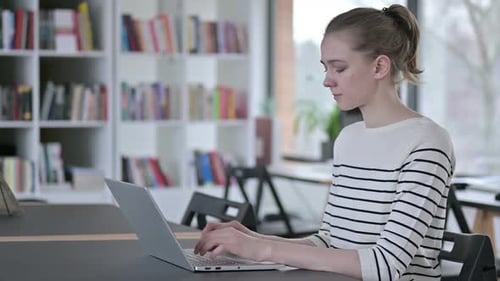 Laptop Use By Young Woman Looking at Camera in Library