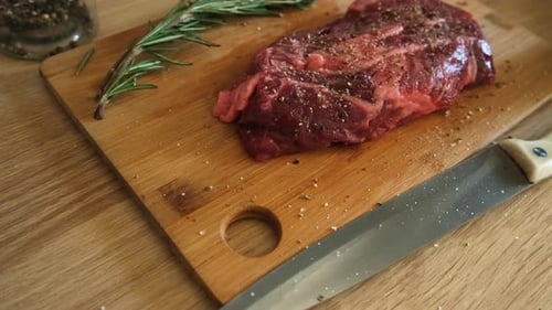 Close Up of Raw Steak with Rosemary on Board