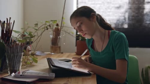 Teen Creates Digital Art on Tablet at Desk