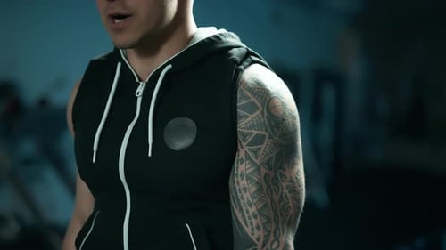 A Handsome Young Muscular Sportsman is Doing Exercise on a Fitness Machine in the Gym