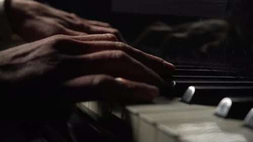 Hands Playing Piano Keys in Dark Lighting