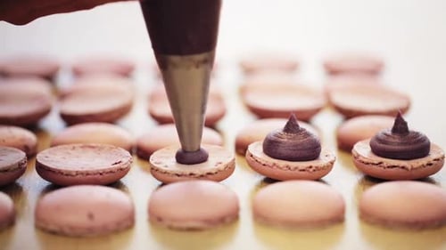 Chocolate Filling Being Piped into Delicate Macarons