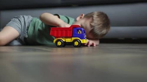 Child Plays with Toy Dump Truck on Floor