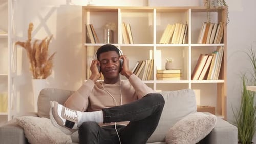 Man Enjoying Music on Couch with Headphones Indoors