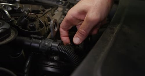 Mechanic Hand Adjusting Tube Under Hood of Car