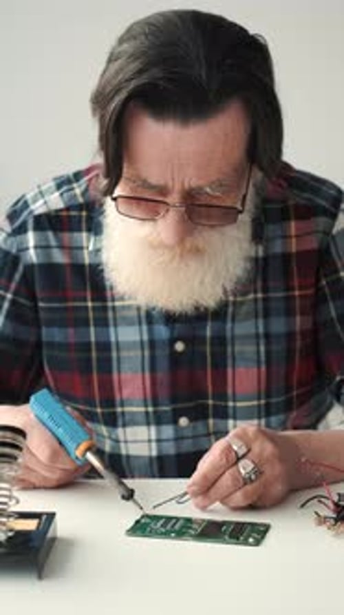 Senior Man Soldering a Circuit Board
