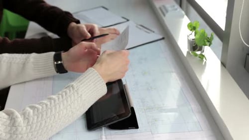 The business team works with construction drawings using a tablet.