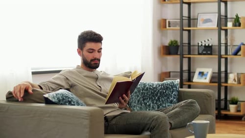 Man Relaxing on Couch Reading a Book