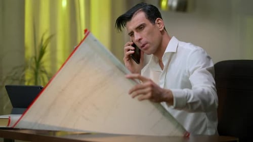 Man on Phone Looking at Blueprints