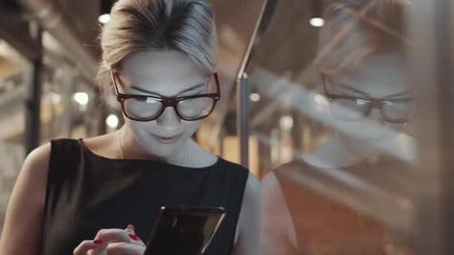 Elegant Blonde Business Lady Messaging on Mobile Phone in Office