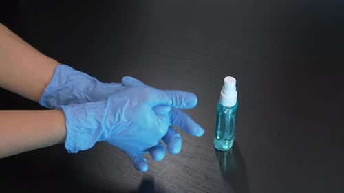 Blue Gloves Spraying Hand Sanitizer for Cleanliness