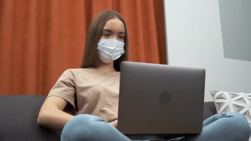 Woman with Mask Working on Laptop at Home