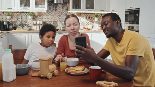 Family looking at smartphone at the kitchen table