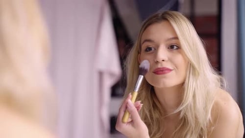 Woman Applying Makeup With Brush in Mirror