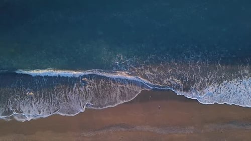 Blick von oben nach unten türkisfarbene Wellen, die am leeren Kiesstrand die Küste erreichen. Meer Goldene Stunde Sonnenuntergang