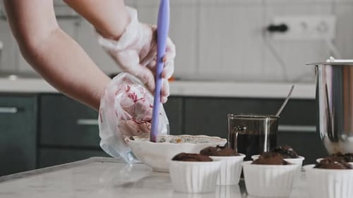 Köchin beim Kuchenbacken mit Kirschfüllung in den Spritzbeutel