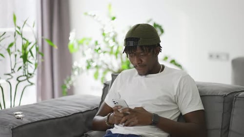 Man Smiling While Using Phone on Couch