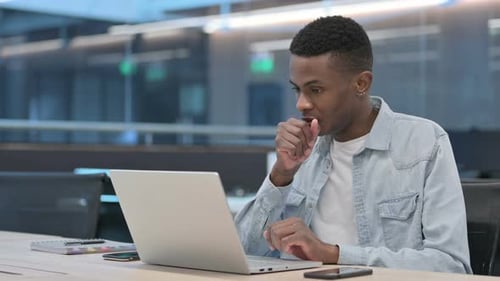 Young Adult Coughing While Using Laptop At Work