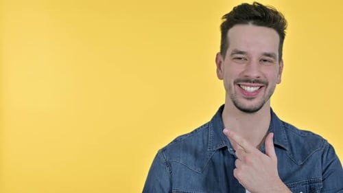 Man Points to Side on Yellow Background