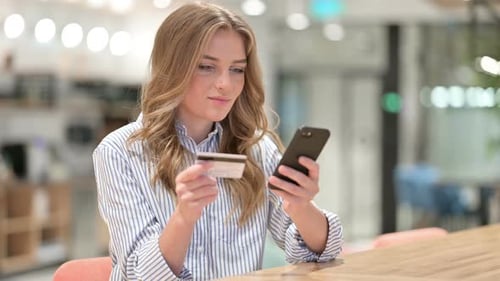 Woman Using Phone and Credit Card in Office