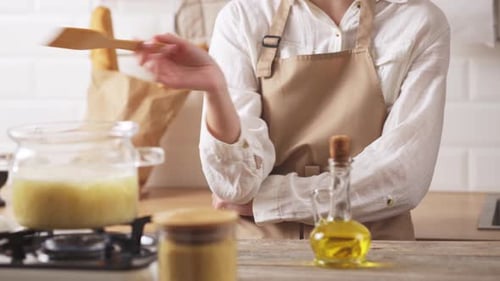 Woman Cooking at Stove in Kitchen Interior