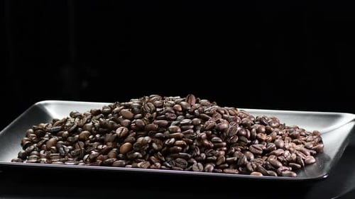 Coffee Beans Rotating on Black Plate