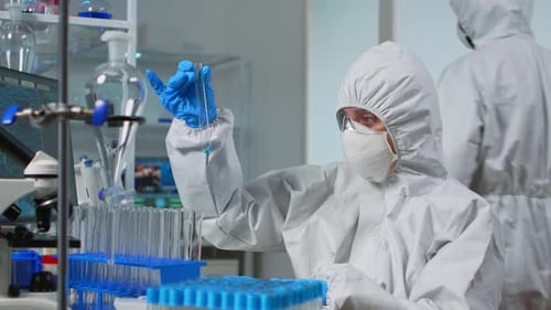 Traje de equipo técnico haciendo experimento comprobando tubo de ensayo